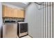 Laundry room with cabinet storage, a modern washer and dryer, and striped wallpaper at 7580 S Monaco Way, Centennial, CO 80112