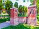 Stone entryway with the Potter Highlands sign, complemented by lush greenery and a clear blue sky at 2715 W 37Th Ave, Denver, CO 80211