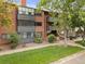 Brick building with green landscaping and mature trees at 534 E 7Th Ave # 101, Denver, CO 80203