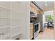 Bright kitchen featuring wood floors, stainless steel appliances, and a pantry with adjustable shelving at 534 E 7Th Ave # 101, Denver, CO 80203