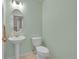 Charming powder room with a pedestal sink, toilet, and a decorative mirror, designed with light green walls at 4006 E Geddes Cir, Centennial, CO 80122