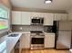 Modern kitchen with stainless steel appliances, white cabinets, and tile backsplash at 5479 E Weaver Ave, Centennial, CO 80121