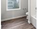 Bathroom featuring wood-look flooring, a window, toilet, and a tub with white tiling at 19018 E 94Th Pl, Commerce City, CO 80022