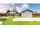 Backyard scene showcasing a basketball hoop, storage shed, and a cozy fire pit in a green, fenced yard at 41 S Fenton St, Lakewood, CO 80226