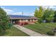 Charming single-story home featuring solar panels, a brick facade, landscaped front yard, and mature trees at 41 S Fenton St, Lakewood, CO 80226
