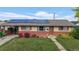 Inviting single-story home with solar panels, red brick details, a well-manicured lawn, and a cozy, covered porch at 41 S Fenton St, Lakewood, CO 80226