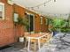 Covered back porch with dining table and chairs, string lights, and a brick exterior at 3560 S Glencoe St, Denver, CO 80237