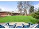 Spacious backyard with lush green lawn, cozy patio seating, and mature trees for shade and privacy at 3560 S Glencoe St, Denver, CO 80237