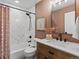 Bathroom features a shower-tub combo with white tile, a wood vanity, and earth tone walls at 3560 S Glencoe St, Denver, CO 80237