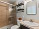 Bathroom features a glass door shower, sink with marble counter, floating shelves and dark hardware at 3560 S Glencoe St, Denver, CO 80237