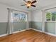 Bedroom with hardwood floors, two windows, green accent wall and white trim at 3560 S Glencoe St, Denver, CO 80237
