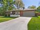 Charming brick ranch home with a well-manicured lawn and a long driveway leading to an attached garage at 3560 S Glencoe St, Denver, CO 80237