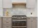 The kitchen has stainless steel oven, modern gray and white cabinets, subway tile backsplash and wood floors at 3560 S Glencoe St, Denver, CO 80237