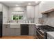 Well-lit kitchen featuring white cabinets, a farmhouse sink, and modern appliances with a window overlooking the backyard at 3560 S Glencoe St, Denver, CO 80237