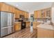 Well-lit kitchen featuring wood cabinets, stainless steel appliances and tile backsplash at 6230 Snowberry Ave, Firestone, CO 80504