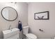 Modern powder room with round mirror, white vessel sink, and a framed art print at 6230 Snowberry Ave, Firestone, CO 80504