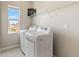 Bright laundry room featuring modern washer and dryer, plus convenient shelving and a window with a view at 18180 W 84Th Pl, Arvada, CO 80007