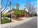 Street view of the townhome featuring stone accents, red garage doors, and mature trees at 1703 Whitehall Dr # 5I, Longmont, CO 80504