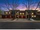 Beautiful exterior view of townhomes with red garage doors, complimented by well-maintained landscaping and scenic dusk sky at 1703 Whitehall Dr # 5I, Longmont, CO 80504