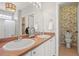 Bright bathroom featuring double sinks, stylish fixtures, and decorative floral wallpaper accenting the toilet area at 19302 E 58Th Pl, Aurora, CO 80019
