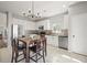 Open-concept kitchen with white cabinets, stainless appliances, and dining area with stylish chandelier at 19302 E 58Th Pl, Aurora, CO 80019