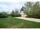 Three-car garage with a long driveway and spacious lawn surrounded by lush trees at 4070 S Hudson Way, Englewood, CO 80113