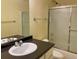 Bright bathroom with a shower-tub combo featuring decorative glass doors and a sleek sink vanity with modern faucet at 1022 Morning Dove Dr, Longmont, CO 80504