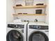 Well-equipped laundry room with modern washer and dryer units and shelving at 5128 W 26Th Ave # 101, Denver, CO 80212