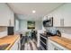 Modern kitchen features butcher block countertops, stainless steel appliances, and white cabinets at 10541 Routt St, Westminster, CO 80021