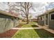 A spacious backyard between the house and garage has a sidewalk and mature trees at 2504 S Yates St, Denver, CO 80219
