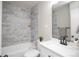 Updated bathroom featuring modern fixtures, marble tiled shower/tub, and a large vanity mirror at 2504 S Yates St, Denver, CO 80219