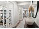 Well-lit hallway with wood floors, white trim, decorative vases, and French doors leading to a stylishly furnished room at 716 N Carrie Ct, Watkins, CO 80137