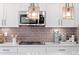 Close-up of modern kitchen features white cabinets, stainless steel microwave, and stylish backsplash at 716 N Carrie Ct, Watkins, CO 80137