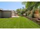 Beautiful backyard featuring a lush lawn, stone wall, and a cozy patio area for relaxation at 621 S Harrison Ln, Denver, CO 80209