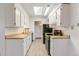 Galley kitchen with skylight, white cabinets, stainless steel appliances, and wood-look flooring at 1820 Newland Ct # 313, Lakewood, CO 80214