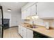 A kitchen with wood countertops, white cabinetry, stainless steel appliances, and stainless steel sink at 1820 Newland Ct # 313, Lakewood, CO 80214