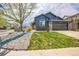 Inviting blue home with a stone-accented garage, lush lawn, and decorative landscaping at 12133 Crabapple St, Broomfield, CO 80020