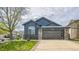 Charming blue home featuring a modern garage, stone accents, and manicured lawn at 12133 Crabapple St, Broomfield, CO 80020