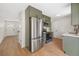 Modern kitchen featuring stainless steel appliances, stylish green cabinetry, and wood flooring at 1205 W 101St Ave, Northglenn, CO 80260