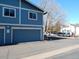 Side exterior view featuring blue garages and a parking area in a sunny environment at 1255 S Wheeling Way, Aurora, CO 80012