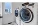 A laundry room with modern washer and dryer on pedestals, a window, and grey tile flooring at 8049 Monte Vista Cir, Littleton, CO 80125