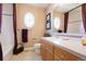 Well-lit bathroom with a white countertop, wooden cabinets, and a decorative oval window at 2174 Meadow Vale Rd, Longmont, CO 80504