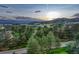 Scenic aerial view of the property surrounded by lush greenery, mountains, and a colorful sunset at 3201 Country Club Pkwy, Castle Rock, CO 80108