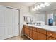 Well-lit bathroom featuring a large mirror, a vanity, tile floors and sliding closet doors at 6237 Trailhead Rd, Highlands Ranch, CO 80130