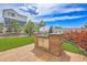 Beautiful backyard with a built-in grill, lush grass, and manicured landscaping under a sunny sky at 21900 E 46Th Pl, Aurora, CO 80019