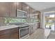 Modern kitchen featuring stainless steel appliances, stylish cabinetry, tile backsplash, and a large window to bring the outdoors in at 21900 E 46Th Pl, Aurora, CO 80019