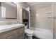 This bathroom features updated cabinets, tile backsplash and shower, and a newer toilet at 7767 Elmwood St, Littleton, CO 80125