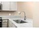 Close-up of a kitchen sink with marble countertops and light gray cabinetry at 7767 Elmwood St, Littleton, CO 80125