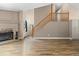 Open living area with hardwood floors, a fireplace, and an adjacent staircase at 7767 Elmwood St, Littleton, CO 80125