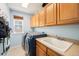 Functional laundry room with blue washer and dryer, ample cabinet space, and a practical utility sink at 10647 Nucla St, Commerce City, CO 80022